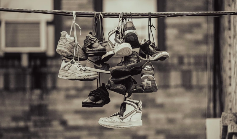 Paires de sneakers Nike accrochées sur un fil, qui font références à la culture streetwear des quartiers.