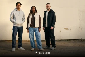 Outfit streetwear unisexe, trois silhouettes en pied, hoodie gris et jean droit, gilet matelassé écru sur hoodie brun et jean baggy clair, veste technique noire et cargo noir.