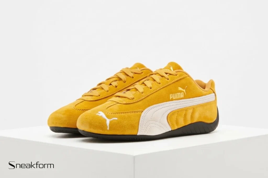 Sneakers tendance 2026, Puma Speedcat en suède jaune moutarde avec bande crème et semelle noire.