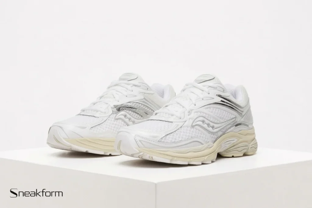 Sneakers tendance 2026, Saucony ProGrid Omni 9 en mesh blanc avec empiècements argentés et semelle crème.
